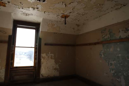 Water damage on walls and ceiling in a brown and white room.